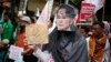 A Muslim woman wears a mask of Myanmar's Foreign Minister Aung San Suu Kyi during a rally against the persecution of Rohingya Muslims, outside the embassy of Myanmar in Jakarta, Indonesia, Nov. 25, 2016. 