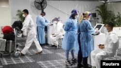 Travelers receive tests for the COVID-19 at a pre-departure testing facility, as countries react to the new coronavirus omicron variant, outside the international terminal at Sydney Airport in Sydney, Australia, Nov. 29, 2021. 