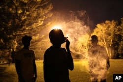 Youths take turns to smoke marijuana in a park in Harare, Zimbabwe, May, 4, 2018.