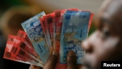 FILE - A man holds Ghana's cedi notes in Accra. Taken 7.3.2007