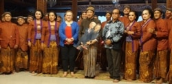 Dalang Purbo Asmoro sambil memegang wayang Biden dan Harris (tengah) beserta kru karawitan melakukan foto bersama pegiat seni budaya asal Amerika Serikat, Kitsie Emerson (tengah- baju merah biru), Sabtu, 30 Januari 2021. (Foto : VOA/ Yudha Satriawan)