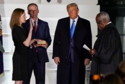 President Donald Trump watches as Supreme Court Justice Clarence Thomas administers the Constitutional Oath to Amy Coney Barrett on the South Lawn of the White House White House in Washington, Monday, Oct. 26, 2020.