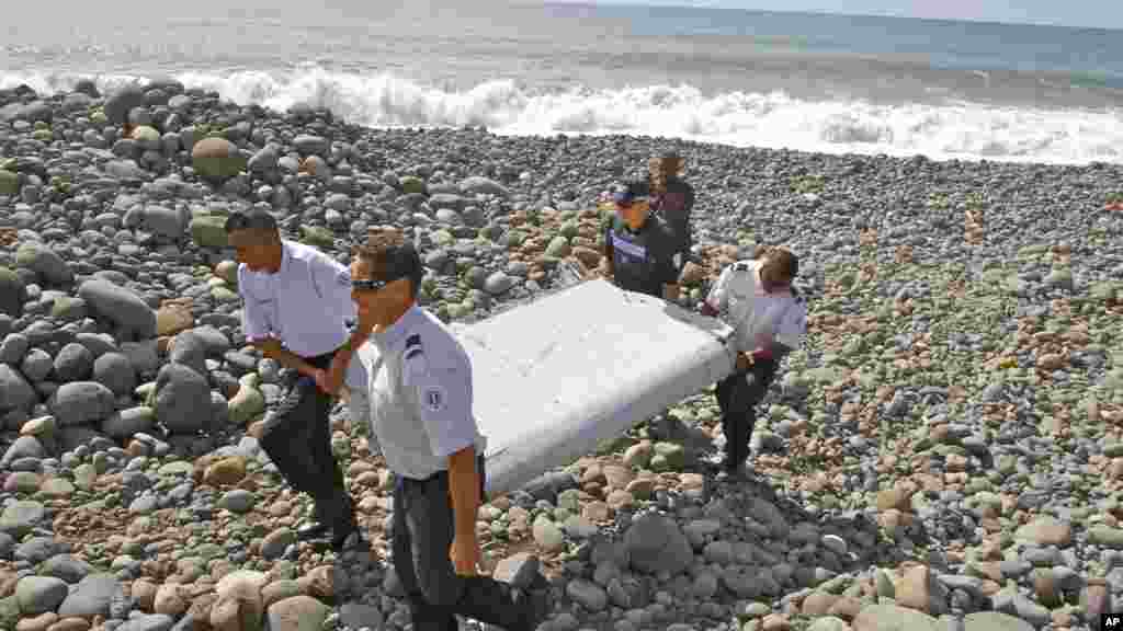Des gendarmes et policiers français portent un morceau d&#39;avion trouvé sur la plage de Saint-André, 29 juillet 2015.