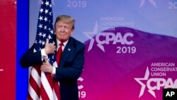President Donald Trump hugs the American flag as he arrives to speak at Conservative Political Action Conference, in Oxon Hill, Md., March 2, 2019.