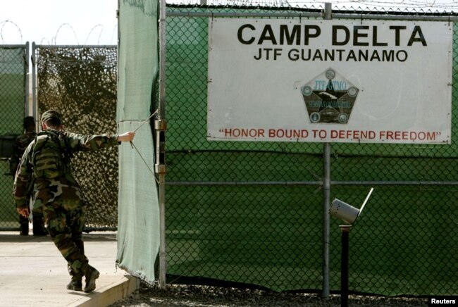 25 Ağustos 2005 yılına ait bu fotoğrafta bir ABD askeri, Küba'nın Guantanamo Koyu'ndaki askeri üste bulunan hapishanenin giriş kapısını kapatırken görüntülenmiş.
