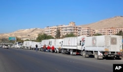 FILE - A convoy of humanitarian aid waits in front of the United Nations Relief and Works Agency (UNRWA) offices before making their way into the government besieged rebel-held towns of Madaya, al-Zabadani and al-Moadhamiya in the Damascus countryside.