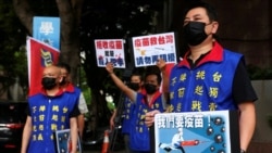 People hold placards calling for Taiwan government to allow the use of COVID-19 vaccines from China