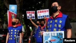 People hold placards calling for Taiwan government to allow the use of COVID-19 vaccines from China