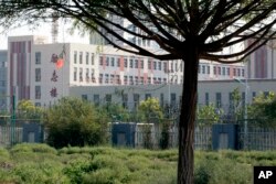 FILE - Barbed wire protects the walls around a cluster of schools on the outskirts of Kashgar, in western China's Xinjiang region, Aug. 31, 2018.