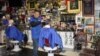 Bennie Botes (far left) and Louis de Hart at work inside their barbershop in Newlands, Johannesburg. The wall holds just a fraction of the rugby memorabilia collected by Botes over the past 50 years. (Darren Taylor for VOA News)