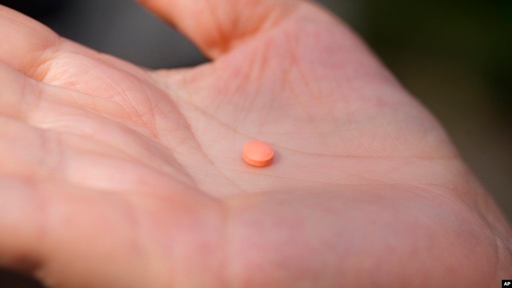 FILE - A woman holds an aspirin pill in the Brooklyn borough of New York on Friday, Oct. 15, 2021. Early study suggests older adults without heart disease should not take daily aspirin to prevent a first heart attack or stroke. (AP Photo/Emma H. Tobin)