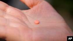 FILE - A woman holds an aspirin pill in the Brooklyn borough of New York on Friday, Oct. 15, 2021. Early study suggests older adults without heart disease should not take daily aspirin to prevent a first heart attack or stroke. (AP Photo/Emma H. Tobin)