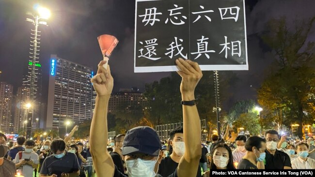 六四31周年香港人首次进行”非法”维园烛光悼念集会，数以万计市民响应，有人高举烛光及标语 （美国之音/汤惠芸）