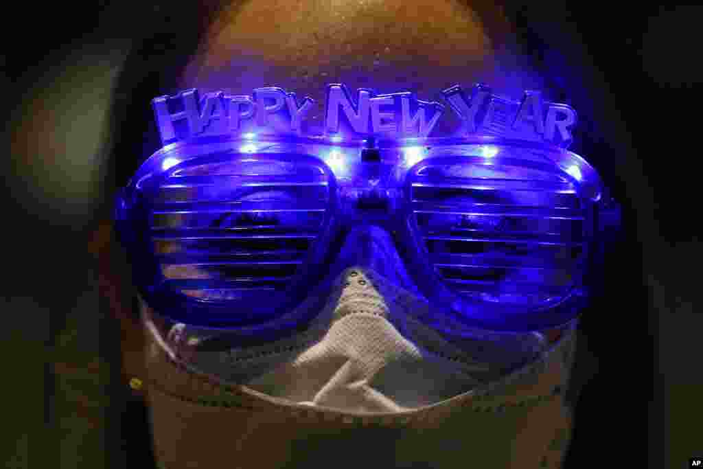 Alejandra Paiz, a tourist from Guatemala who is visiting Mexico for the holidays, wears festive glasses to mark New Year&#39;s Eve at the Angel of Independence monument in Mexico City.
