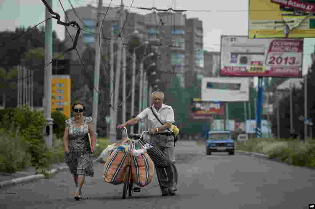 People carry their belongings using a bicycle as they leave Slovyansk, eastern Ukraine, June 9, 2014.