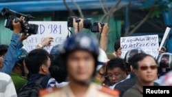 Police and security personnel film protesters holding placards which read, "Haiyang 981 oil rig get out of Vietnam (left)" and "Take China to the international court" (right) during an anti-China protest in Vietnam's southern Ho Chi Minh city May 18, 2014.