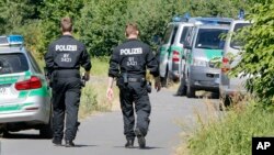 Police officers walk to the crime scene near the river Main, background, where a 17-year-old man from Afghanistan was shot the night before, near Wuerzburg, Germany, Tuesday, July 19, 2016.