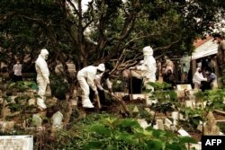 Penggali kuburan mengenakan pakaian pelindung diri (APD) mengubur korban COVID-19 di pemakaman di Lhokseumawe, Aceh, 18 Mei 2021. (Foto: Azwar Ipank / AFP)