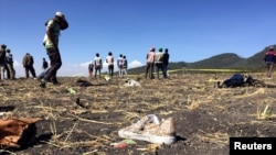 Orang-orang berjalan melewati puing-puing pesawat Ethiopian Airlines dengan nomor penerbangan ET 302 yang jatuh dekat Kota Bishoftu, tenggara Ibu Kota Addis Ababa, 10 Maret 2019.