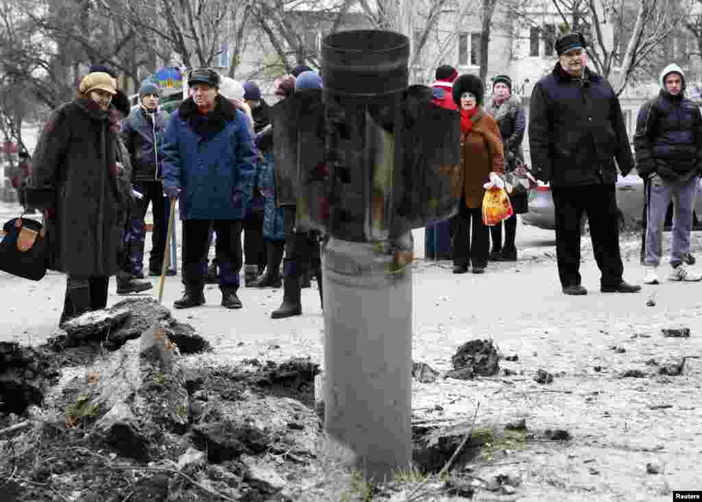 People look at the remains of a rocket on a street in the town of Kramatorsk, eastern Ukraine, Feb. 10, 2015.