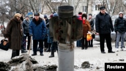 People look at the remains of a rocket shell on a street in the town of Kramatorsk, eastern Ukraine, Feb. 10, 2015. T