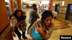 Women carrying children run for safety as armed police hunt gunmen who went on a shooting spree in Westgate shopping center in Nairobi, Sept. 21, 2013.