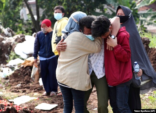 Anggota keluarga saat pemakaman kerabatnya di Pemakaman Srengseng Sawah yang diperuntukkan bagi mereka yang meninggal karena COVID-19, di Jakarta, Rabu, 9 Juni 2021. (Foto: AP/Tatan Syuflana)