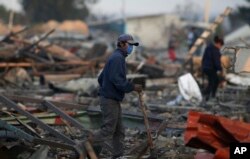 FILE - A man walks through the scorched ground of the open-air San Pablito fireworks market, in Tultepec, outskirts of Mexico City, Mexico, Dec. 20, 2016.