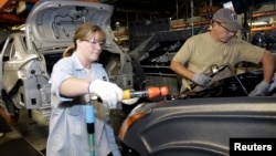 在密西根州一家福特汽车制造厂里，一名女工与男工人一起工作