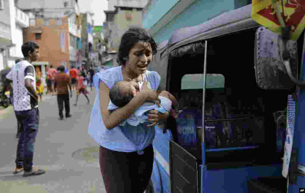 A woman living near St. Anthony&#39;s shrine runs for safety with her infant after police found explosive devices in a parked vehicle in Colombo, Sri Lanka.