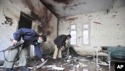 Policemen survey the site of a suicide bomb attack in a police station in Peshawar February 24, 2012.