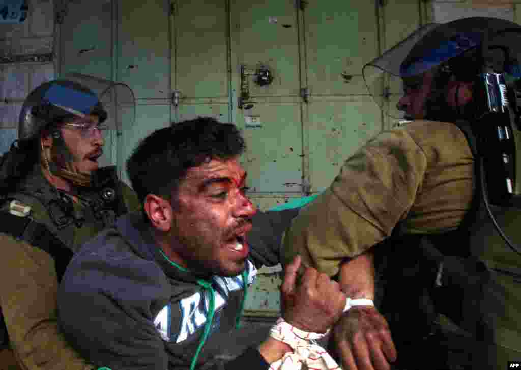 Palestinian protester resists arrest by Israeli soldiers during clashes in the old city of Hebron, following a protest demanding the reopening of Shuhada Street, the one-time heart of the city. 