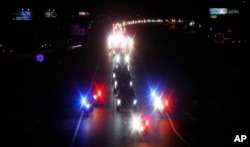 With a police escort, a long procession accompanies the hearse carrying the late Arizona Sen. John McCain along Interstate 17 on the way to Phoenix, Aug. 25, 2018, in Anthem, Ariz.