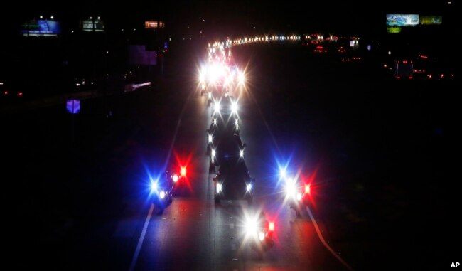 With a police escort, a long procession accompanies the hearse carrying the late Arizona Sen. John McCain along Interstate 17 on the way to Phoenix, Aug. 25, 2018, in Anthem, Ariz.