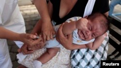 A mother holds her baby as he receives a pneumococcal vaccination during a national vaccination campaign in Managua, April 15, 2013.