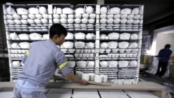 In this Jan. 22, 2016 photo, worker Nguyen Thanh Vuong carries a shelf of potteries, preparing them for the kiln in a factory in Bat Trang village, Hanoi, Vietnam. (AP Photo/Hau Dinh)
