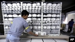 In this Jan. 22, 2016 photo, worker Nguyen Thanh Vuong carries a shelf of potteries, preparing them for the kiln in a factory in Bat Trang village, Hanoi, Vietnam. (AP Photo/Hau Dinh)