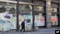 A man walks next to the windows of a closed shop in downtown Milan, Italy, April 12, 2012. 