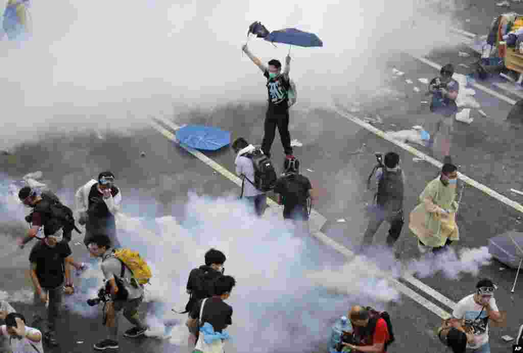 Protesters walk through tear gas used by riot police after thousands of people blocked a main road at the financial central district in Hong Kong.