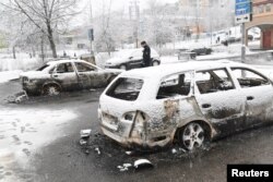 A policeman investigates a damaged car in the Rinkeby suburb outside Stockholm, Sweden, Feb. 21, 2017.