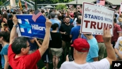 A supporter of Democratic presidential candidate Hillary Clinton and a Republican presidential candidate Donald Trump supporter hold signs as they attend a Memorial Day parade, May 30, 2016, in Chappaqua, N.Y.