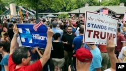 FILE - A supporter of Democratic presidential candidate Hillary Clinton and a Republican presidential candidate Donald Trump supporter hold signs as they attend a Memorial Day parade, in Chappaqua, New York, May 30, 2016.
