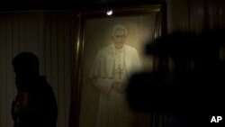 在梵蒂岡採訪的記者在教宗本篤16世的畫像前走過