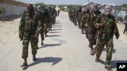 FILE - Members of the al-Shabab militant group patrol on foot on the outskirts of Mogadishu.