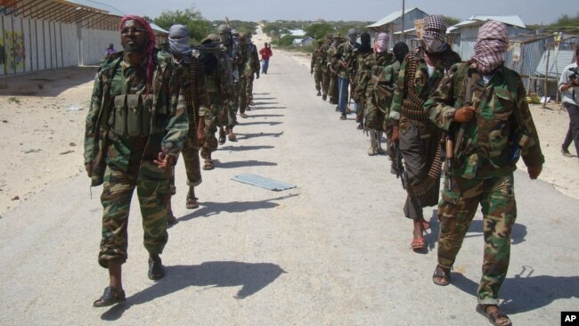 FILE - Members of the al-Shabab militant group patrol on foot on the outskirts of Mogadishu.