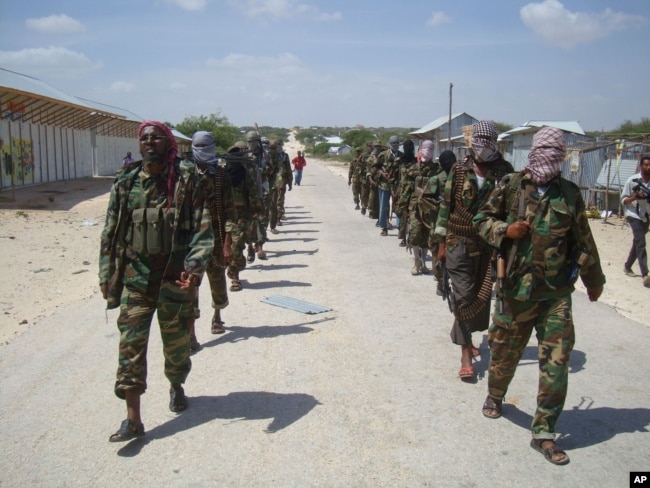 FILE - Members of Somalia's al- Shabab militant group patrol on foot on the outskirts of Mogadishu.