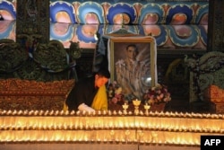 This photograph released on October 13, 2016 by Bhutan's Royal Office for Media on Bhutanese King Jigme Khesar's Facebook page shows King Jigme Khesar at the Kuenra of the Tashichhodzong in Thimpu lighting candles next to a portrait of Thailand's King Bhu