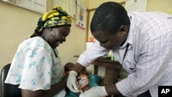 Iren Salama (left) holds her baby Pendo as it is given a malaria vaccination in a medical trial at a clinic in the Kenya coastal town of Kilifi, Nov 23, 2010 (file photo)