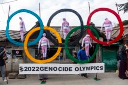 FILE - Exile Tibetans use the Olympic Rings as a prop as they hold a street protest against the holding of 2022 Winter Olympics in Beijing in Dharmsala, India, Feb. 3, 2021.