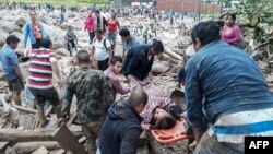 A handout picture released by the Colombian Army press office shows people helping to carry a woman after mudslides following heavy rains, in Mocoa, Putumayo, on April 1, 2017. (AFP PHOTO / EJERCITO DE COLOMBIA)